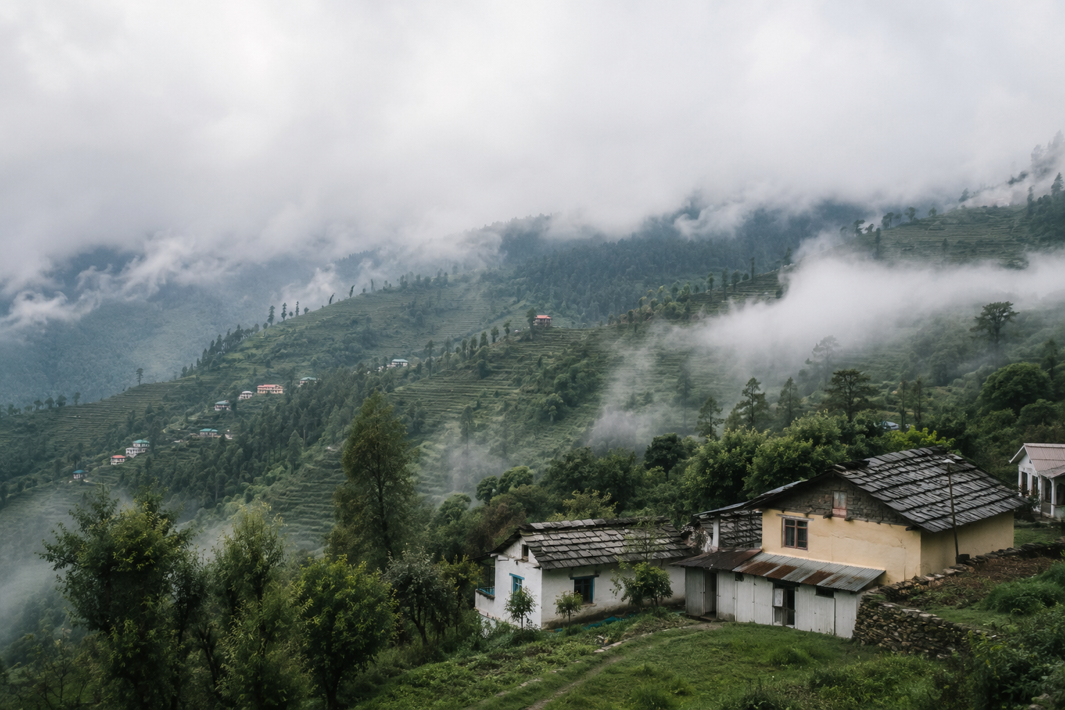 A small quiet hill village with mist over green slopes and just a few houses